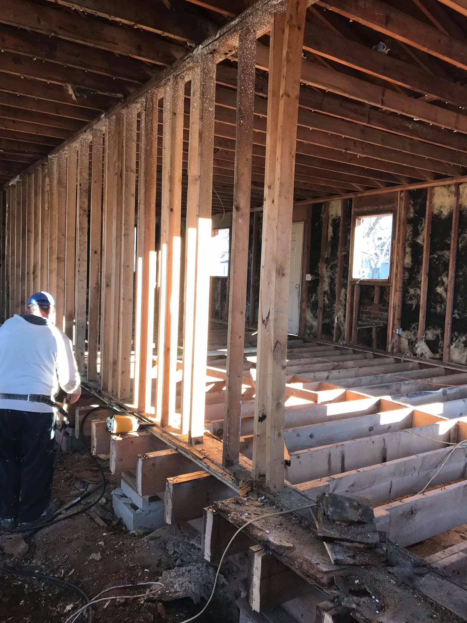 A worker inside a house under construction, the new stud framing exposed